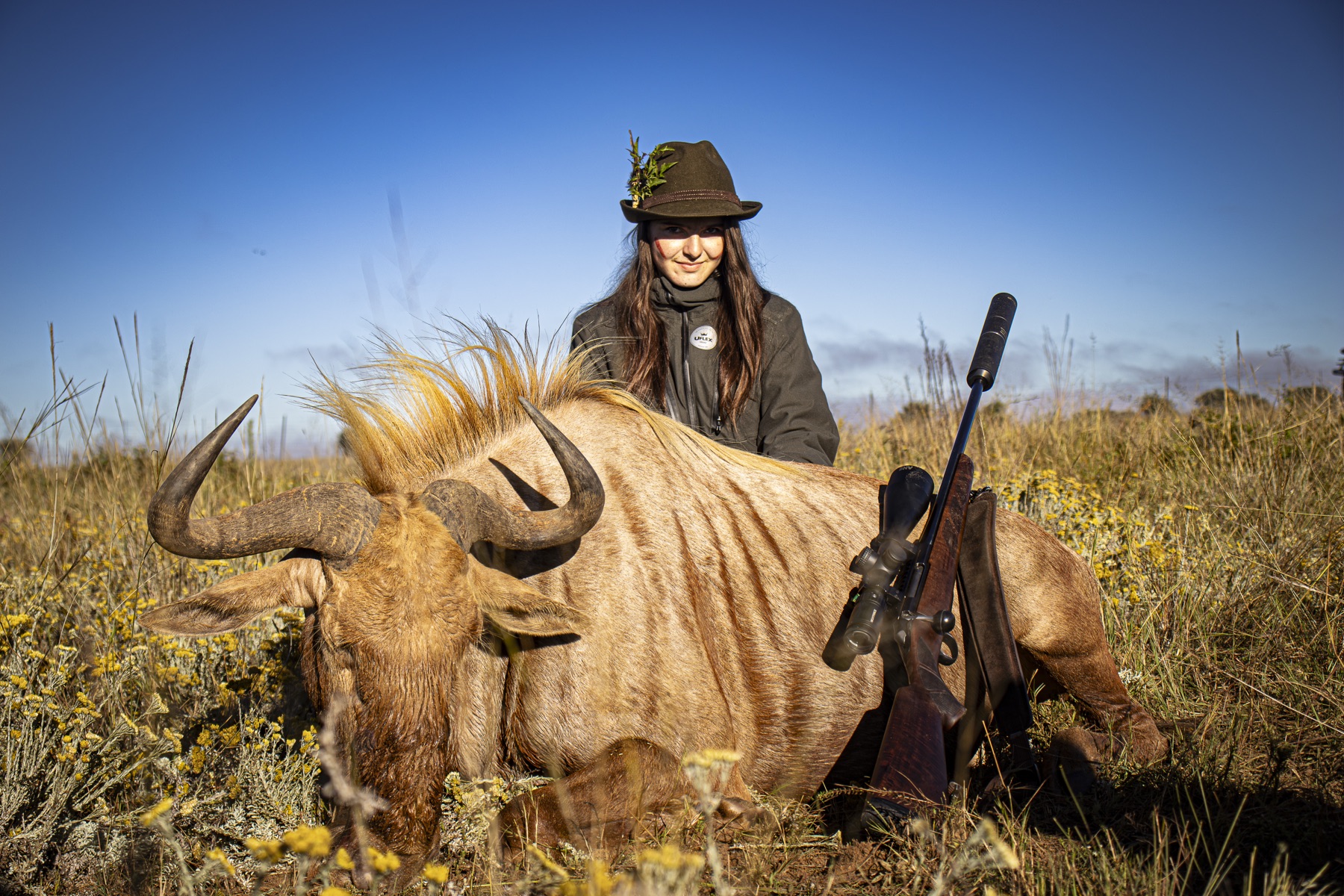 Hunter with a golden wildebeest trophy in tall grass