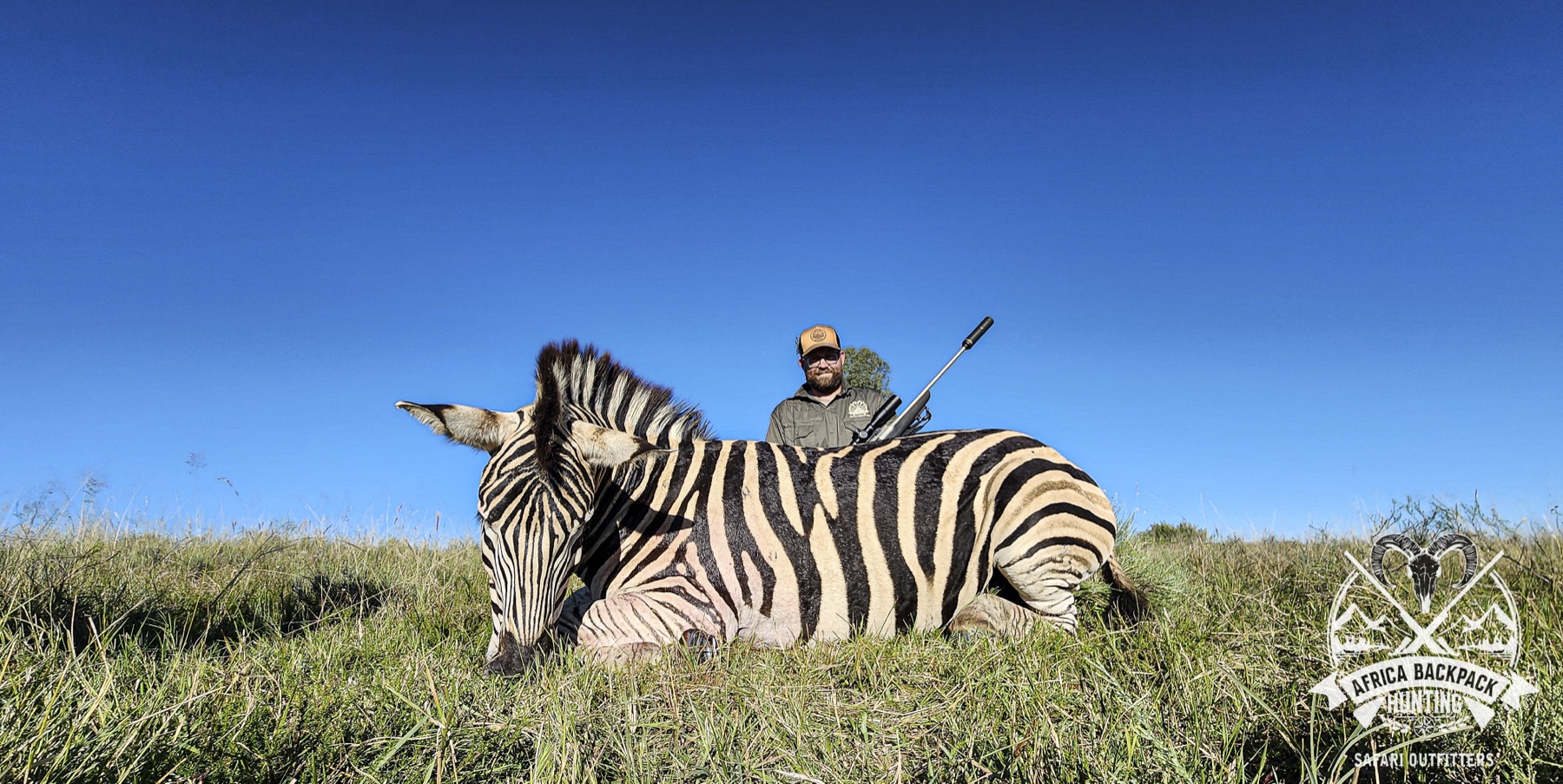 Hunter with a zebra trophy on the open plains